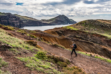 Girl hiking rocky cliffs clear near water of Atlantic Ocean bay Ponta de Sao Lourenco, the island...