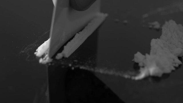 A rolled banknote snorting a line of cocaine powder. Drug Abuse. Sniffing Cocaine lines. White powder on black table. Macro shot.