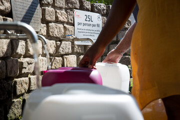 Collecting natural spring water with day zero water crisis with plastic water bottle at Newlands...