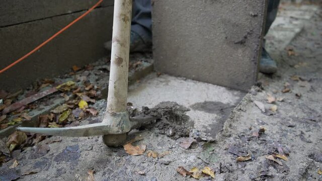 Construction worker pulling out the tile from footpath with mattock