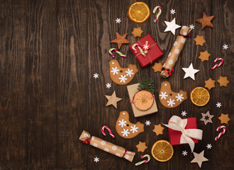 Christmas holiday background with homemade gingerbread cookies, candy canes, gift boxes on dark wooden table.