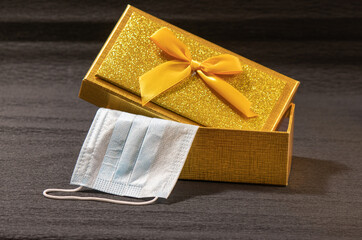 Yellow gift box with medical mask on black background