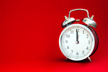 Beautiful vintage silver alarm clock on a bright red background. Time concept. Holiday routine