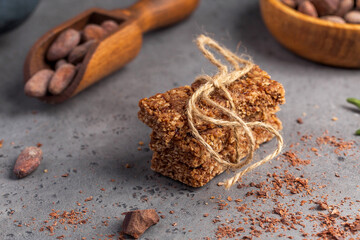 Granola bar with chocolate on a gray background with cocoa beans. Healthy snack, vegan snack