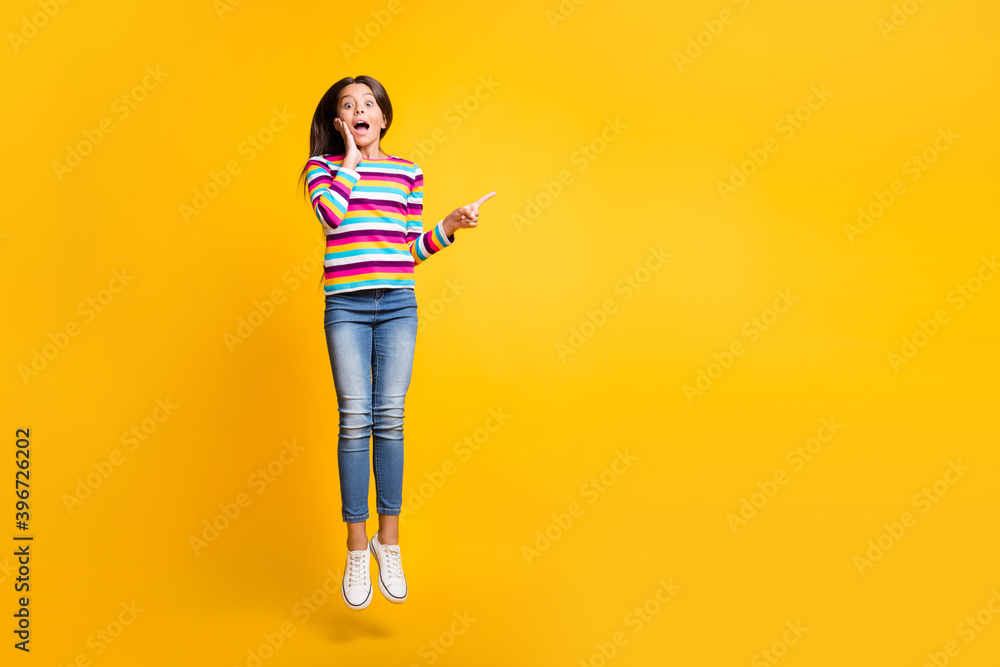 Sticker Full length body size photo of amazed jumping high schoolgirl pointing at blank space isolated on vibrant yellow color background