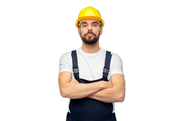 profession, construction and building - male worker or builder in yellow helmet and overall with crossed arms over white background