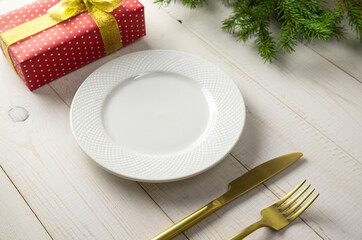 Christmas table setting with white plate and decorations on white background.