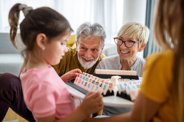 Fototapeta premium Portrait of happy elderly couple and grandchildren playing together