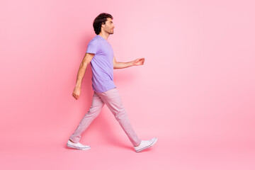 Fototapeta na wymiar Full body profile photo of handsome person walking empty space purple outfit isolated on pink color background