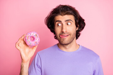 Photo of hungry addicted young man look hold doughnut lick lip isolated on shine pink color background - obrazy, fototapety, plakaty