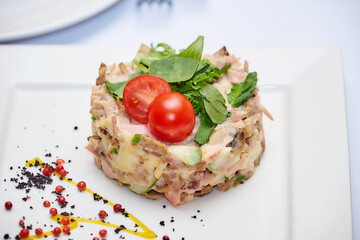 Russian meat salad mayonnaise for dinner. Mayonnaise russian meat salad on white plate background. Salad with bovine tongue meat, cucumbers, mushroom, mayonnaise top view, flat lay lunch in restaurant