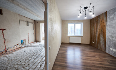 Two empty rooms with modern plastic window, heating radiators and heating inderfloor pipes before...