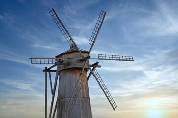 Old wooden windmill on blue sky background at sunset