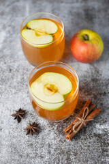 Fototapeta na wymiar Hot apple cider or punch on gray concrete background. Traditional Christmas or New Year warming spicy beverage with cinnamon, star anise. Non-alcoholic drink recipe idea for cold weather.