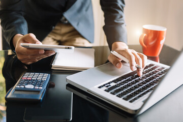 Women counting coins on calculator taking from the piggy bank. hand holding pen working on calculator to calculate on desk about cost at home office..