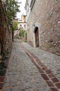 Fototapeta Old building with wooden door on empty village road that is made of stone.