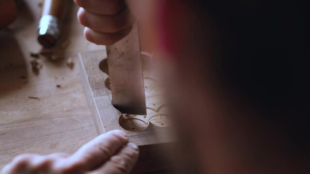 close up. a woodcarver makes a wooden tray. The craftsman processes the walnut board with a flat impact chisel. the sound of carpentry tools