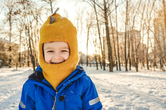 Boy amile and squinted at sun. Winter, park, copy space. Close-up portrait.