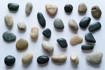 白い紙の背景に置いた複数の小石。平置きの俯瞰撮影。