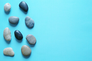 青い紙の背景に置いた小石のグループ。平置きの俯瞰撮影。