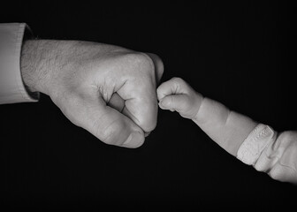 
babies and father's fists on the black background