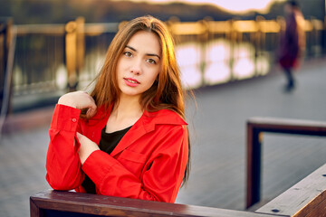 Young woman in the rays of the sunset in an urban environment. An open, direct look, long hair dyed by the sun.