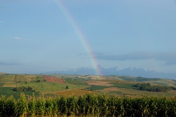 A rainbow that occurs in rural farmland.