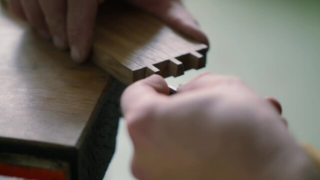 close up. a woodworker carves a dovetail joint into an oak plank with a wood chisel. carpentry, craftsmanship, handicrafts. the sounds of carpentry tools