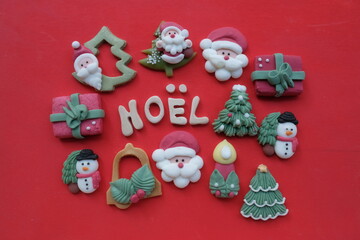 Creative french Merry Christmas, Noel, with wooden letters and marzipan Christmas symbols over red color background