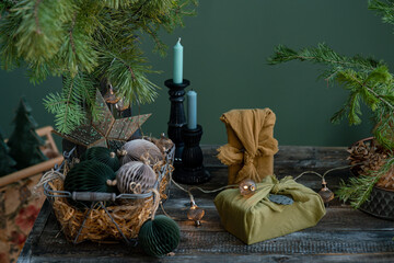 Smiling child unwraps the Christmas gift box near the fir branches decorated with Christmas ornaments. Eco-friendlyfabric reusable gifts with handmade paper balls