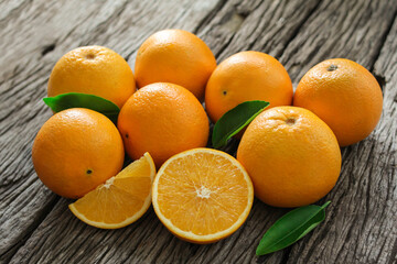fresh orange fruits with leaves on wooden table.