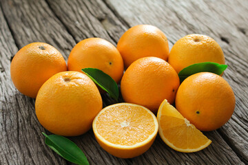 fresh orange fruits with leaves on wooden table.