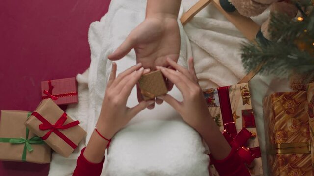 A girl wrapped in a blanket receives a small box. Holiday concept from above