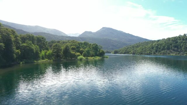Dolly in flying over sun reflected Lake Steffen surrounded by Nahuel Huapi National Park forest, Patagonia Argentina.