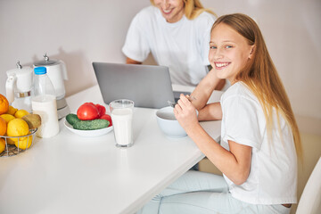 Obraz premium Joyous teen and her busy female parent in the kitchen