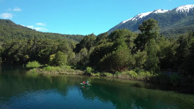 Panning left of two men dry fly fishing in a kayak near the Shore in Lake Steffen, mountains in background, Patagonia Argentina.