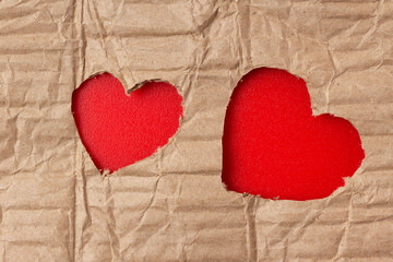 Hearts cut out in a cardboard sheet on a red background