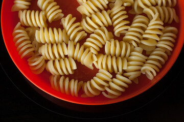 Part of a bright plate with pasta on a black background
