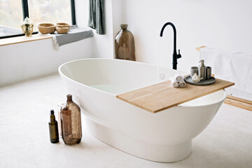 White bathtub fills with foam water in a modern apartment with stylish loft-style interior design, home decor. Spa concept, relaxation. Soft selective focus.