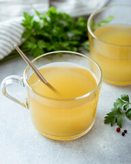 bone broth in a glass cup on a light background, selective focus