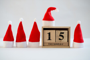 Cube wooden calendar showing date on 15th December with small Santa hats over white background....