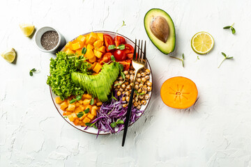 vegan, detox Buddha bowl dish with avocado, tomato, red cabbage, chickpea, fresh lettuce salad, pumpkin, persimmon Healthy balanced eating. Top view