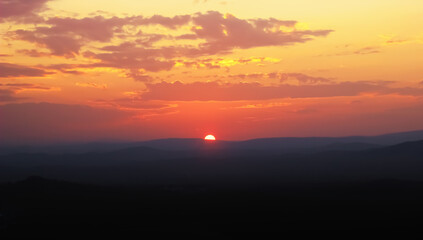 the sun sets behind the mountains on the horizon - a beautiful sunset