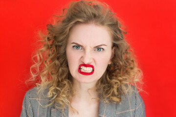 Screaming, hate, rage. Emotional angry woman is angry on red studio background. Emotional, young face, web banner. Expressive facial emotions