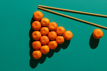 Tangerines are laid out on a billiard table in the form of a classic pyramid of 16 balls with long pasta imitating billiard cues