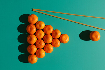 Tangerines are laid out on a billiard table in the form of a classic pyramid of 16 balls with long pasta imitating billiard cues
