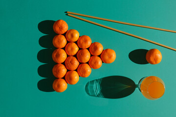 Tangerines are laid out on a billiard table in the form of a classic pyramid of 16 balls with long pasta imitating billiard cues and a glass of tangerine juice
