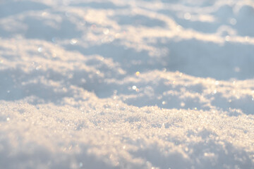 Macro shot background of fresh white snow at the sunset. Snowflakes texture. Snow texture winter background. Shiny snow with bokeh sun rays.