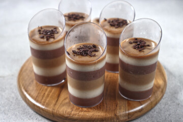 Triple layered pudding made from chocolate, vanilla and coffe in glass.