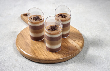 Triple layered pudding made from chocolate, vanilla and coffe in glass.